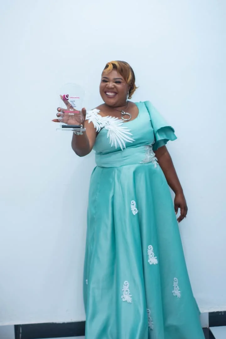 CEO smiling and holding an event-industry award in a turquoise gown