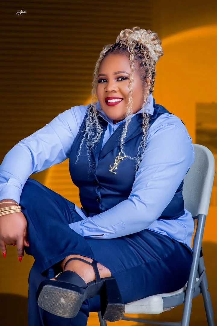 Chichi The Event Planner CEO smiling in a navy suit, portrait with warm golden background